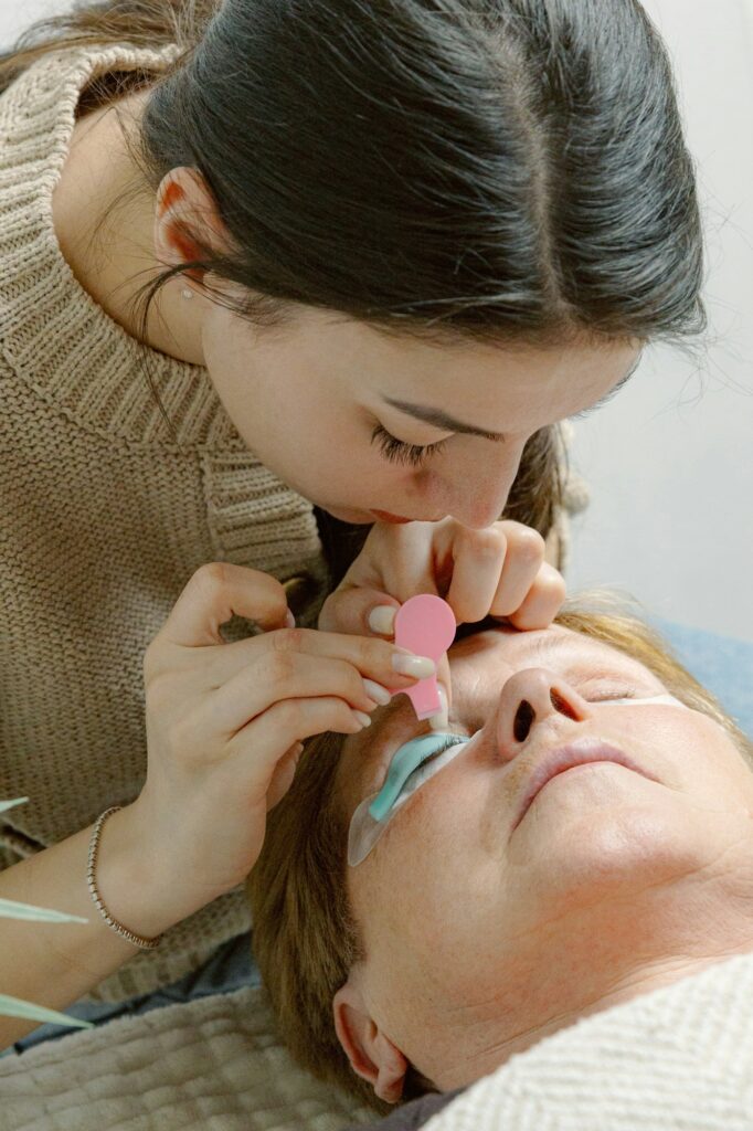 A girl cosmetologist laminates women's eyelashes.