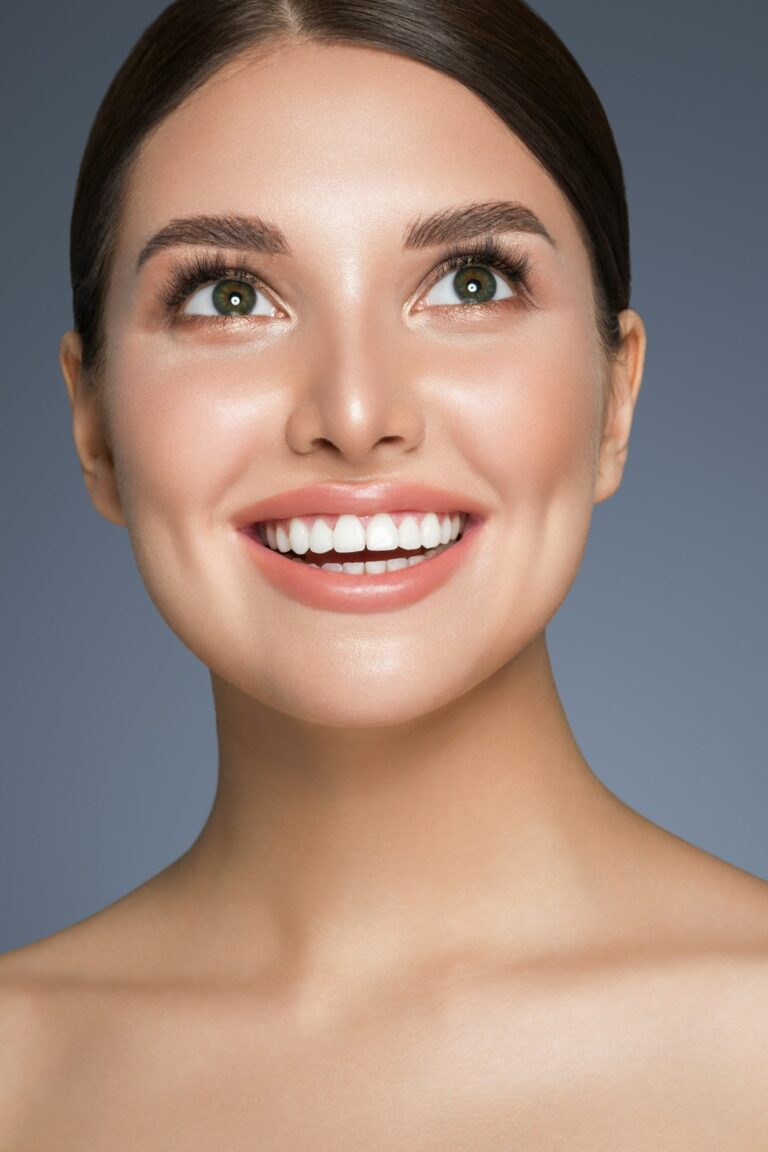 Beautiful woman with healthy teeth smile clean fresh skin portrait. Studio shoot. Gray background.