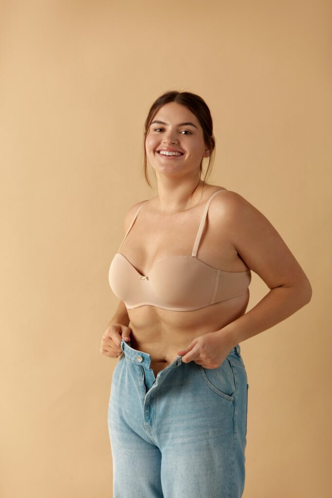 Plus Size Woman in Jeans. Overweight Smiling Woman Demonstrating Weight Loss