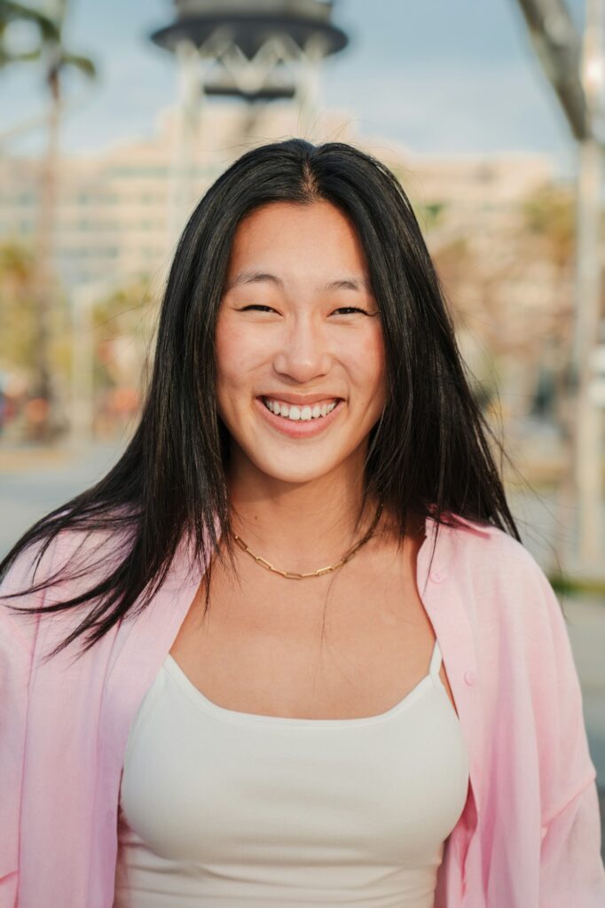 Vertical individual portrait of happy asian young adult woman smiling with perfect white teeth